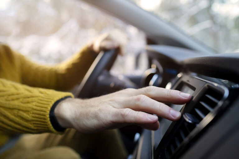 Közeli kép egy kézről az autoklímához nyúlva